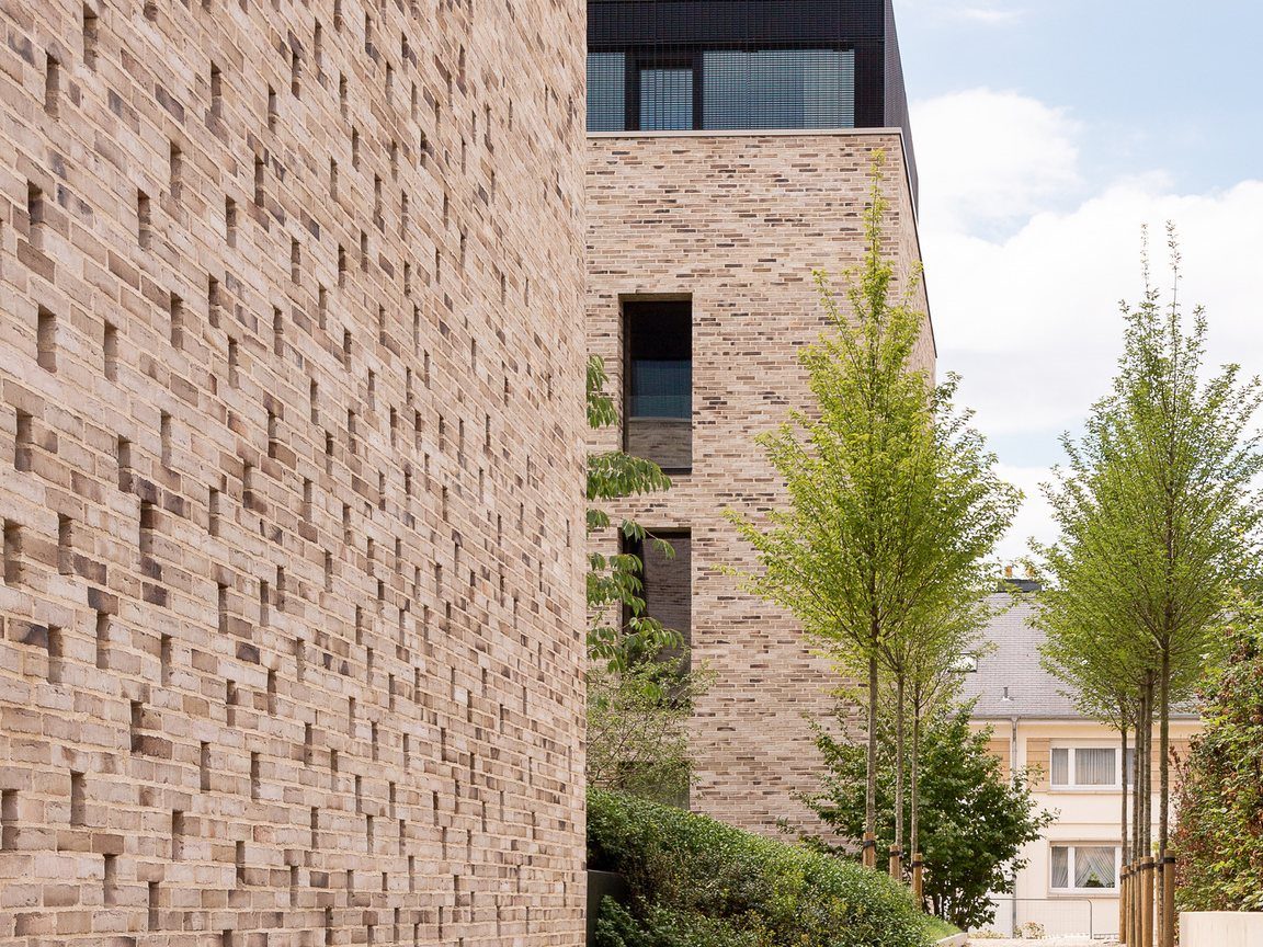 Les Charmes by Bauergroup: textured brick façades, young trees and sky