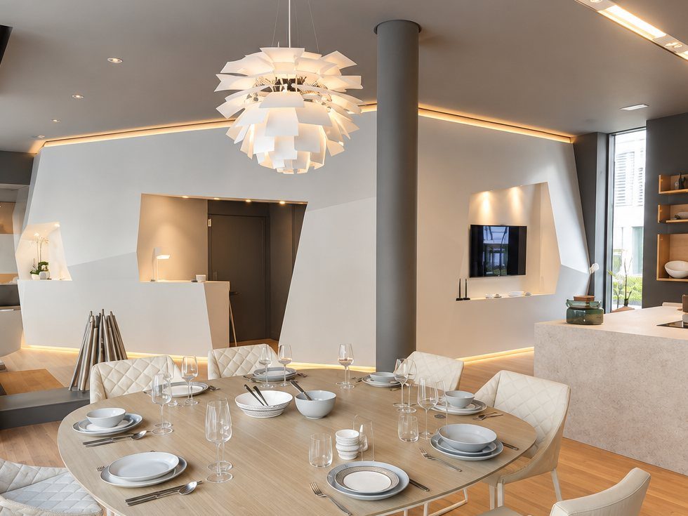 Inside Home & Tailor: faceted white walls with lit niches, a set dining table and a sculptural pendant lamp