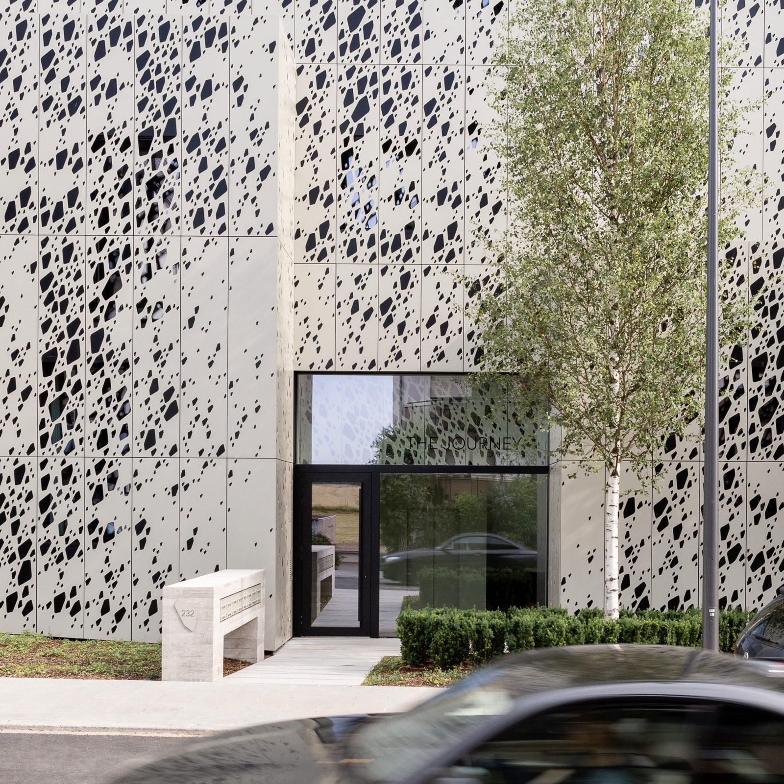 A perforated metal façade around a glass entrance